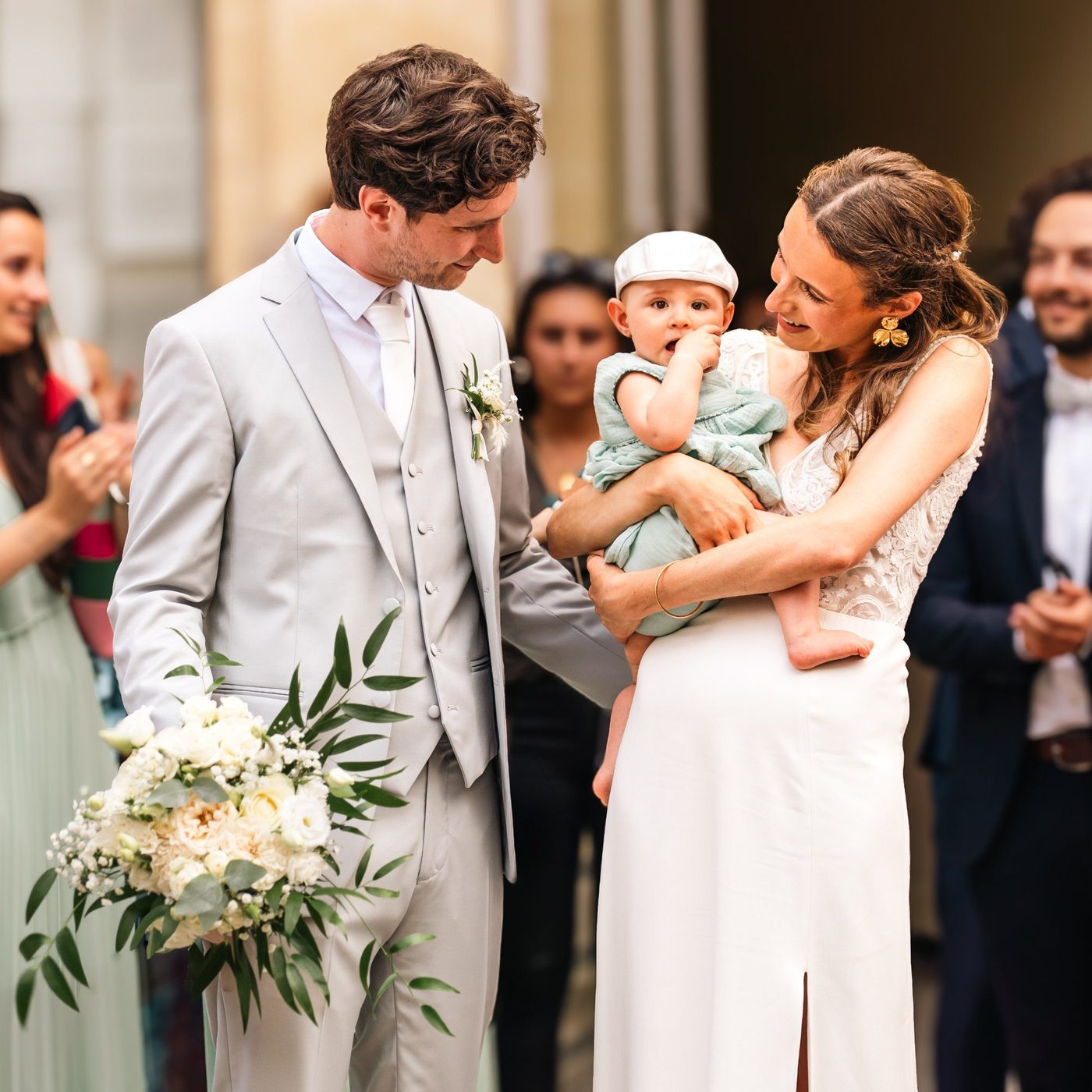 Couple de mariés avec leur bébé à la sortie de la mairie