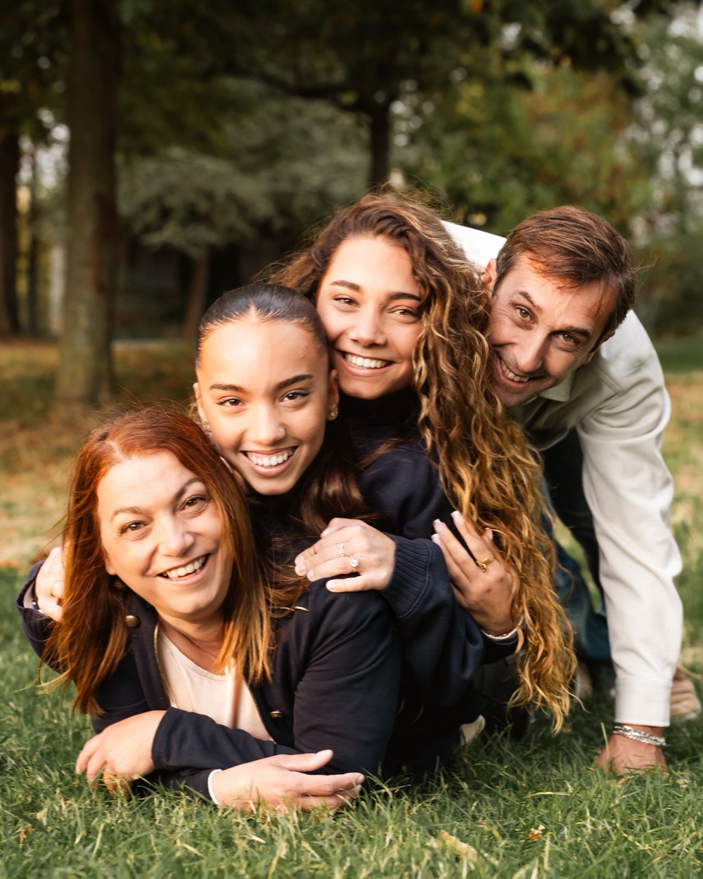 Une famille empilée dans l'herbe, souriante, un homme penché au-dessus des autres.